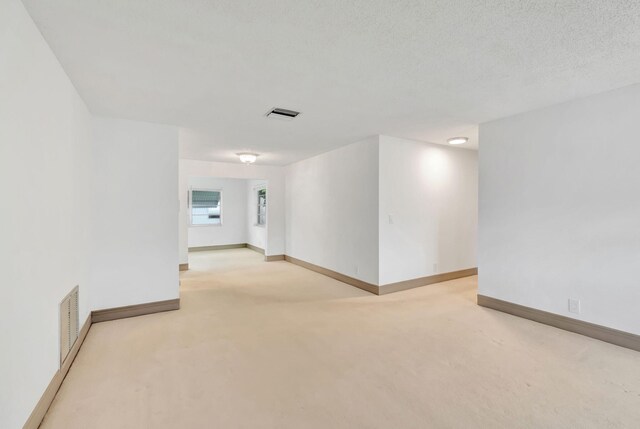 spare room with a textured ceiling and light colored carpet