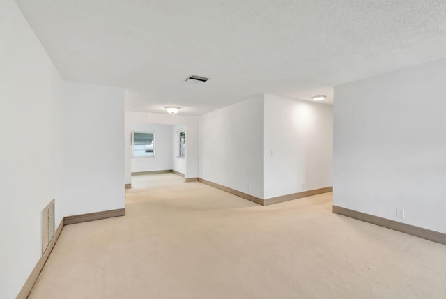 unfurnished room featuring light colored carpet and a textured ceiling