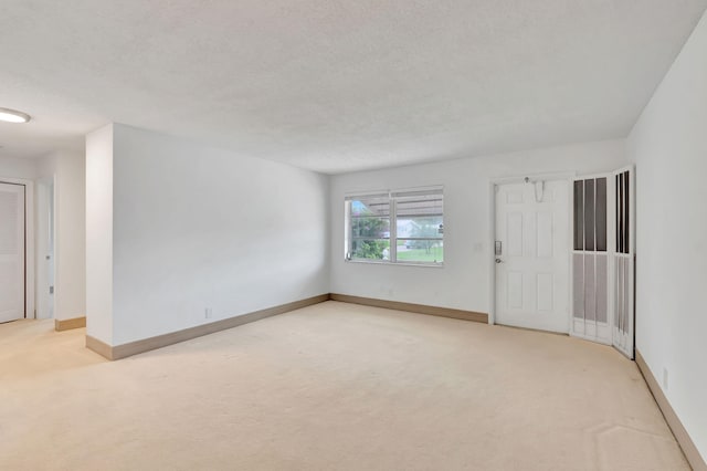 empty room with light carpet and a textured ceiling