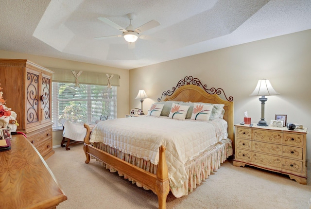 bedroom featuring carpet flooring, a textured ceiling, a raised ceiling, and ceiling fan