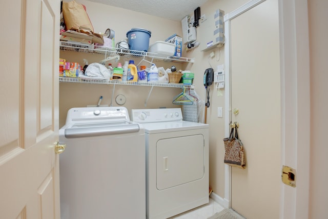 laundry area with washer and clothes dryer, light tile patterned floors, and a textured ceiling