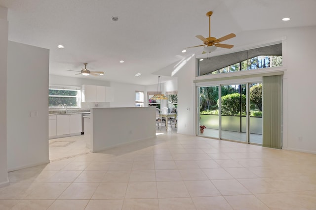 unfurnished living room featuring ceiling fan, light tile patterned floors, a healthy amount of sunlight, and lofted ceiling