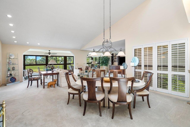 dining space featuring ceiling fan, light carpet, and high vaulted ceiling