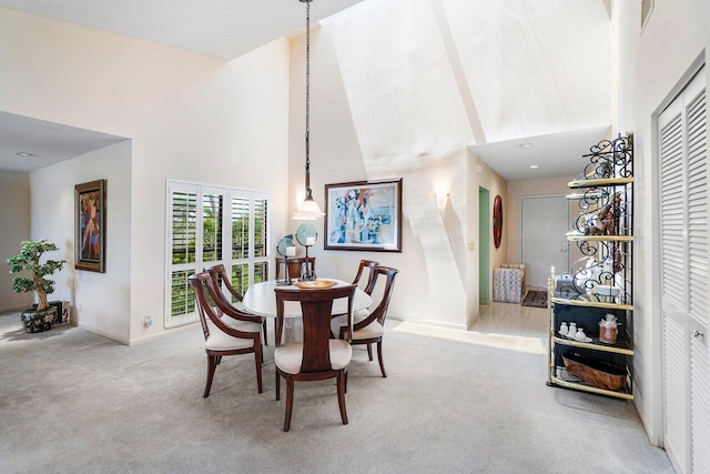 dining room with light carpet and a towering ceiling