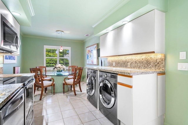 washroom with ornamental molding, independent washer and dryer, and light tile patterned flooring