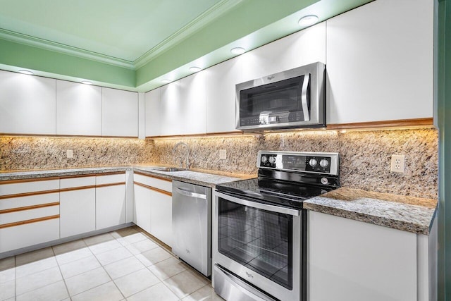 kitchen with white cabinetry, appliances with stainless steel finishes, light tile patterned flooring, ornamental molding, and sink