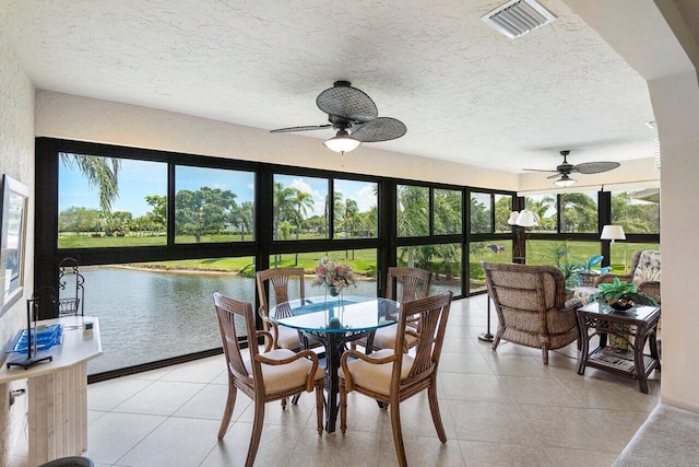 sunroom featuring ceiling fan and a water view