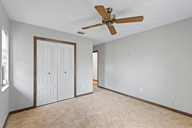 unfurnished bedroom with a closet, ceiling fan, a textured ceiling, and light colored carpet