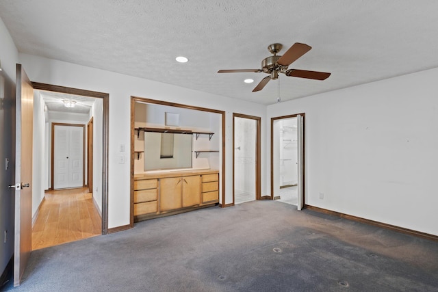 unfurnished bedroom featuring carpet, a textured ceiling, and ceiling fan