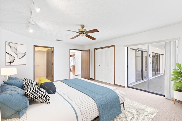 carpeted bedroom with ensuite bathroom, a textured ceiling, access to exterior, rail lighting, and ceiling fan