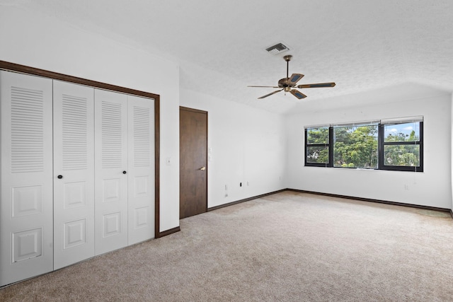 unfurnished bedroom featuring a textured ceiling, light colored carpet, and ceiling fan