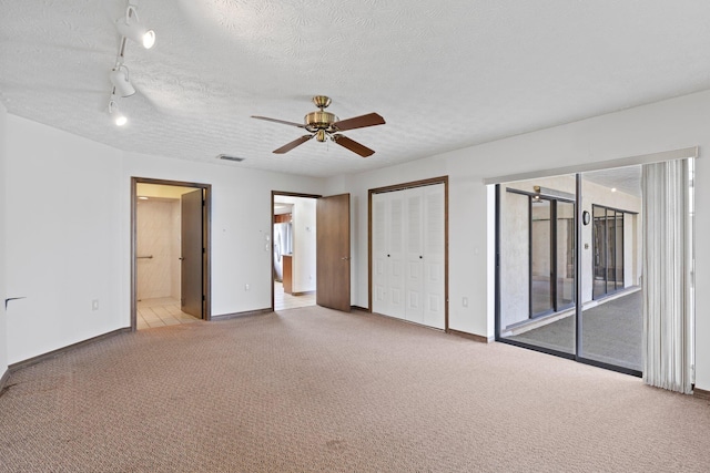 unfurnished bedroom featuring ceiling fan, a textured ceiling, access to exterior, a closet, and light colored carpet