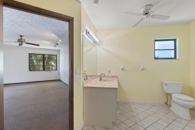 bathroom with toilet, tile patterned flooring, vanity, a textured ceiling, and ceiling fan