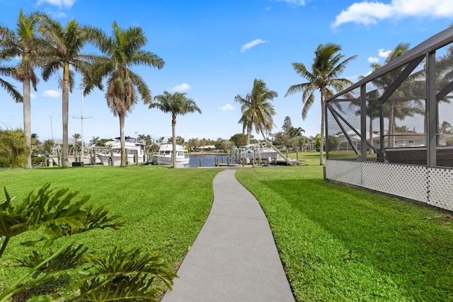 view of yard featuring a water view, a boat dock, and glass enclosure