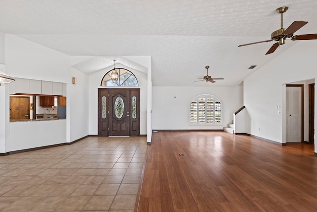 entryway with light hardwood / wood-style flooring, a textured ceiling, ceiling fan, and vaulted ceiling