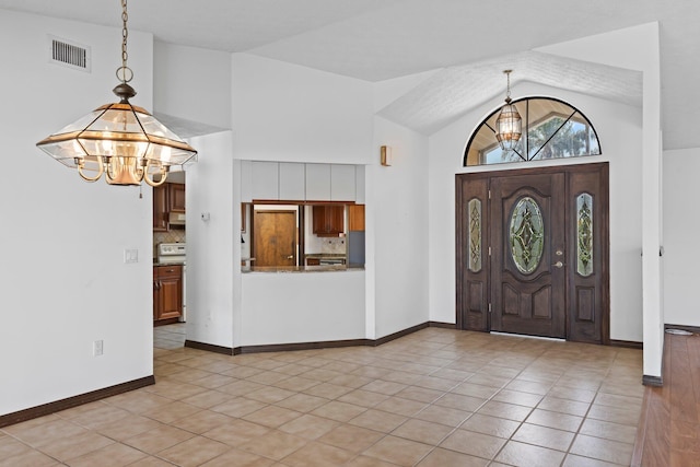 entryway featuring light tile patterned flooring, a notable chandelier, a textured ceiling, and high vaulted ceiling