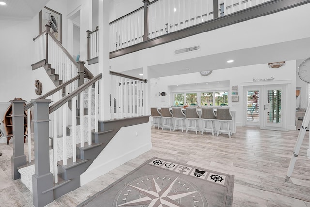 stairway featuring wood-type flooring, a towering ceiling, and french doors