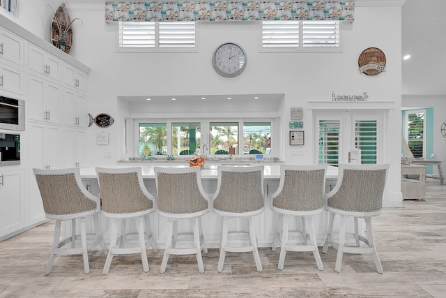 kitchen with a center island with sink, oven, white cabinets, and a kitchen bar