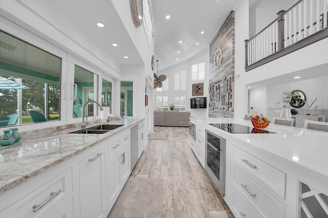 kitchen with white cabinets, sink, light stone countertops, light wood-type flooring, and appliances with stainless steel finishes