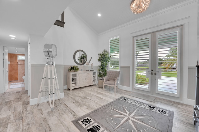 foyer entrance featuring light hardwood / wood-style flooring, crown molding, a wealth of natural light, and french doors