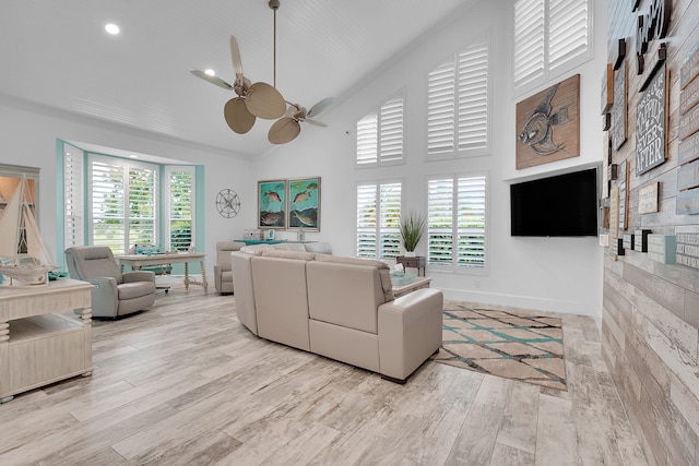 living room with light hardwood / wood-style floors, high vaulted ceiling, ceiling fan, and a healthy amount of sunlight