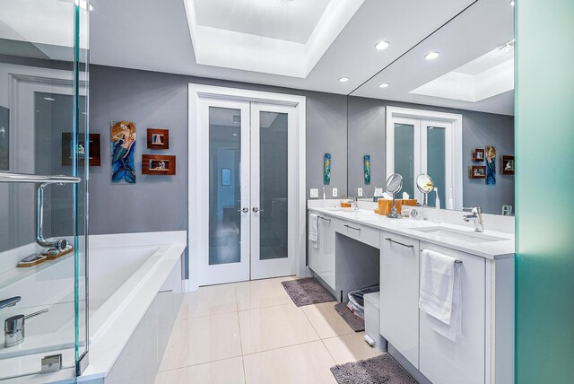 bathroom featuring french doors, double vanity, a tray ceiling, tile patterned floors, and separate shower and tub