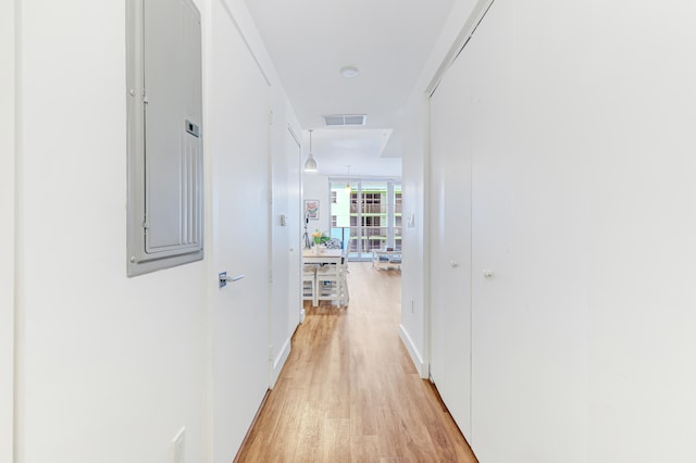 hallway featuring electric panel and light wood-type flooring