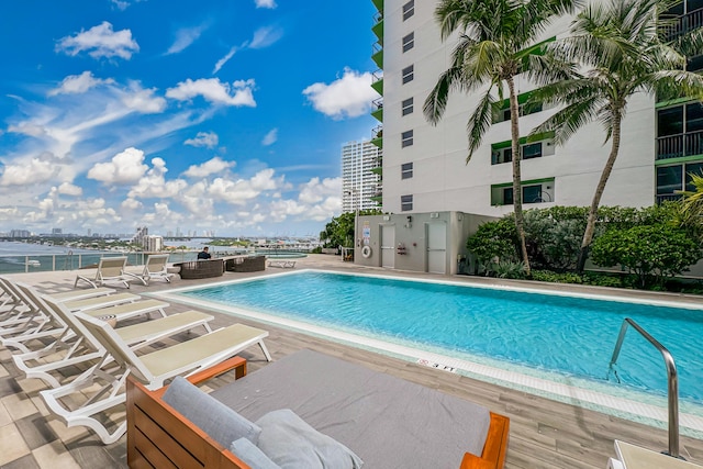 view of pool featuring a water view and a patio