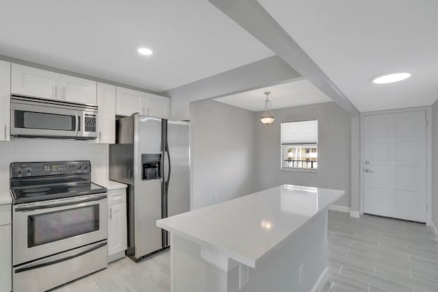 kitchen with tasteful backsplash, stainless steel appliances, pendant lighting, white cabinets, and a kitchen island