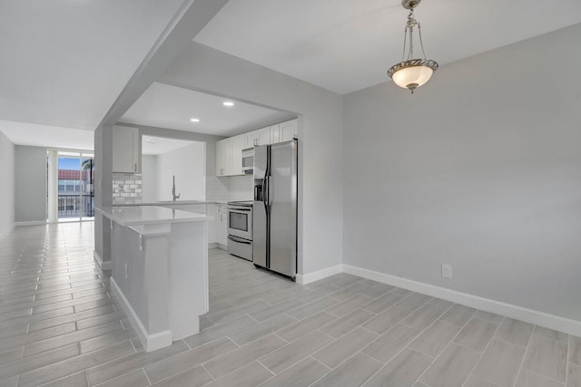 kitchen with stainless steel appliances, sink, pendant lighting, decorative backsplash, and white cabinetry