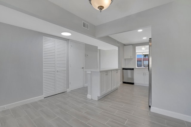 kitchen featuring white cabinetry, backsplash, kitchen peninsula, and stainless steel dishwasher