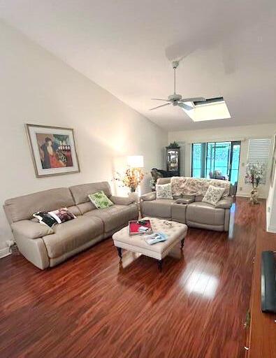 living room featuring ceiling fan, dark wood-type flooring, and vaulted ceiling