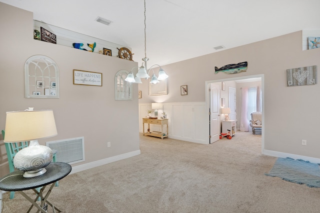 living area with an inviting chandelier and light colored carpet