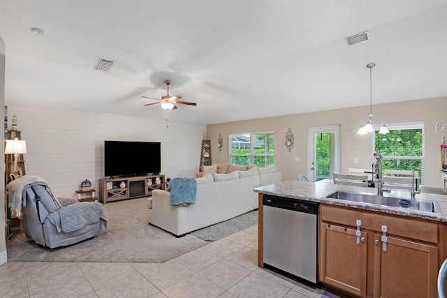 kitchen featuring hanging light fixtures, light tile patterned floors, stainless steel dishwasher, ceiling fan with notable chandelier, and sink