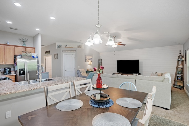 carpeted dining area with sink, vaulted ceiling, and ceiling fan with notable chandelier