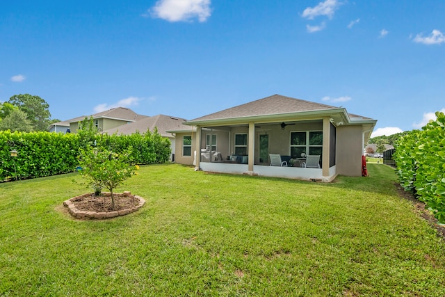 rear view of house with a sunroom, a lawn, and ceiling fan