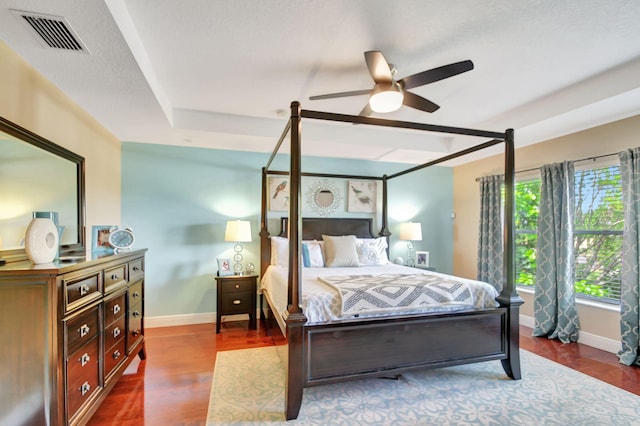 bedroom featuring ceiling fan, hardwood / wood-style floors, and a tray ceiling