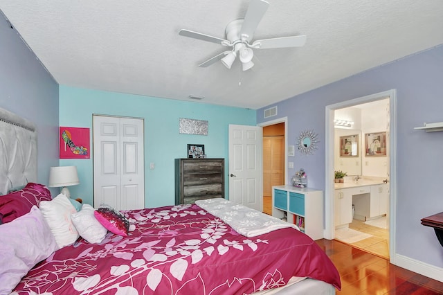 bedroom featuring a textured ceiling, a closet, wood finished floors, and visible vents