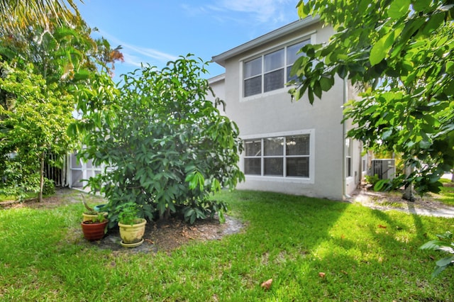 back of property featuring a lawn and stucco siding
