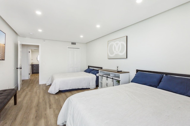 bedroom with a closet, recessed lighting, baseboards, visible vents, and wood finished floors