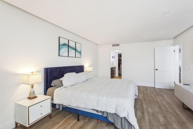 bedroom featuring baseboards, visible vents, and wood finished floors