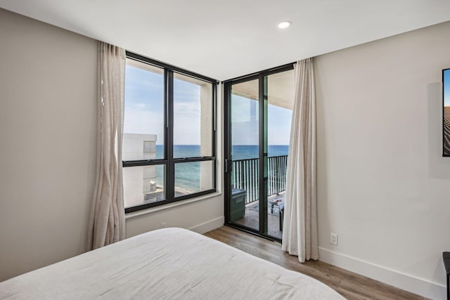 bedroom with multiple windows, a water view, baseboards, and access to exterior