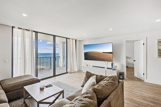 living area featuring floor to ceiling windows, light wood-style floors, baseboards, and recessed lighting