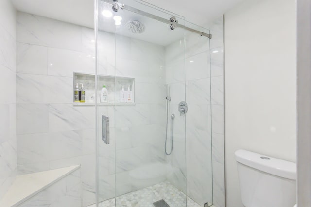 full bath with toilet and a marble finish shower