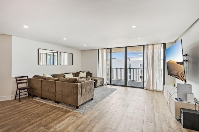 living area with a wall of windows, wood finished floors, and recessed lighting