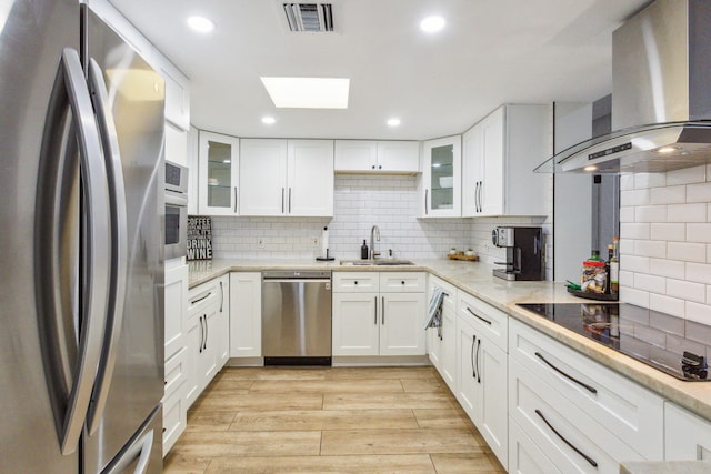 kitchen with light hardwood / wood-style flooring, stainless steel appliances, wall chimney range hood, sink, and backsplash