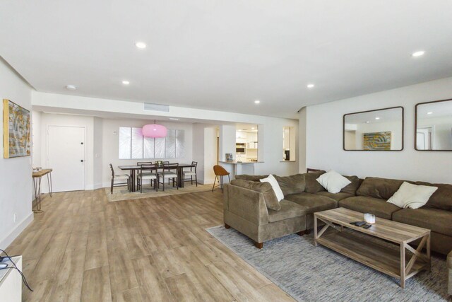 living room featuring light wood-type flooring, visible vents, and recessed lighting