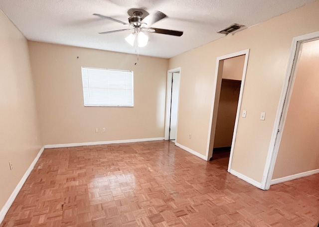 unfurnished bedroom featuring a spacious closet, ceiling fan, a textured ceiling, and light parquet flooring