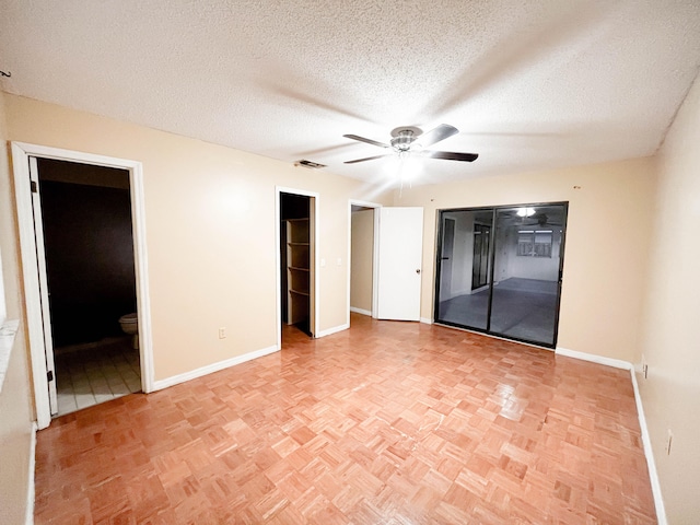 unfurnished bedroom with a textured ceiling, ceiling fan, light parquet flooring, ensuite bathroom, and a walk in closet