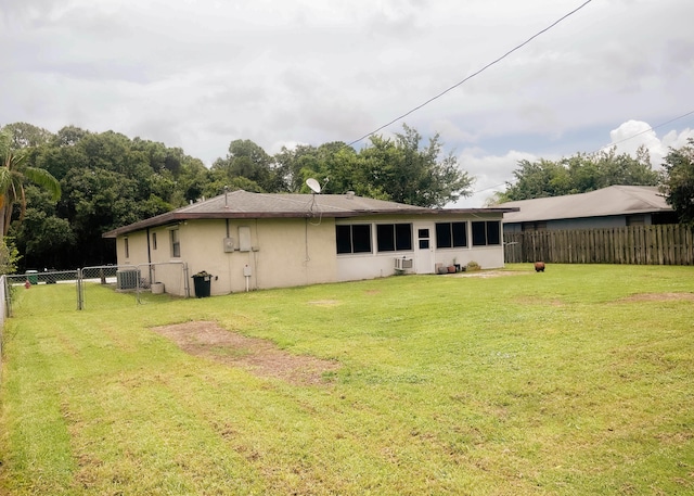 rear view of property featuring central AC unit and a yard